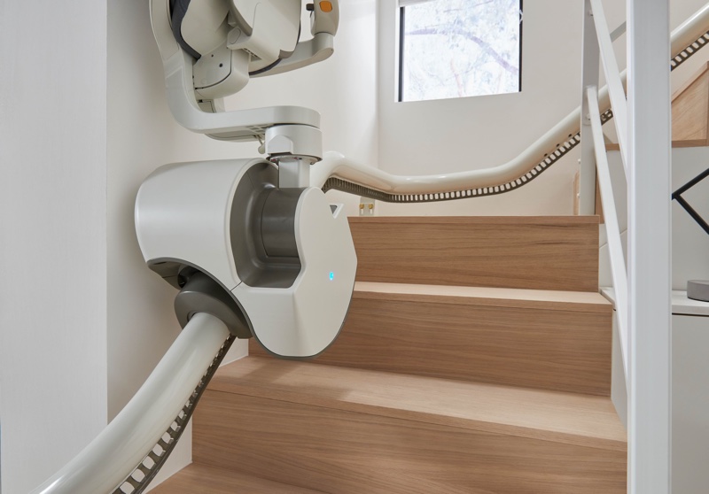 woman on top of stairs using curved stair lift