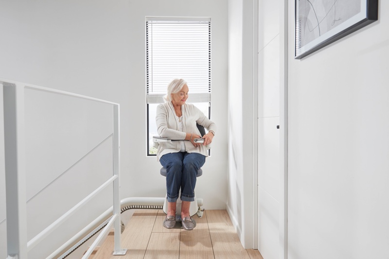 flow x curve stair lift with woman arriving at top of stairs