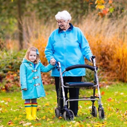 Grandma using walker and grandaughter in park