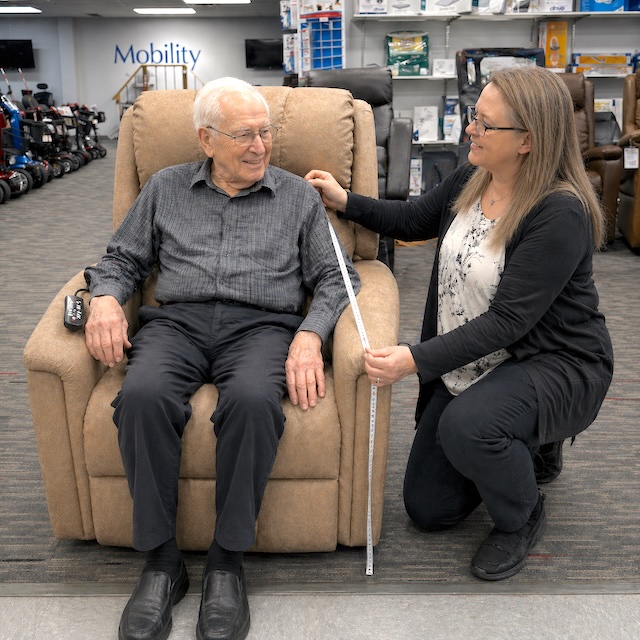 store manager measuring client for liftchair fitting